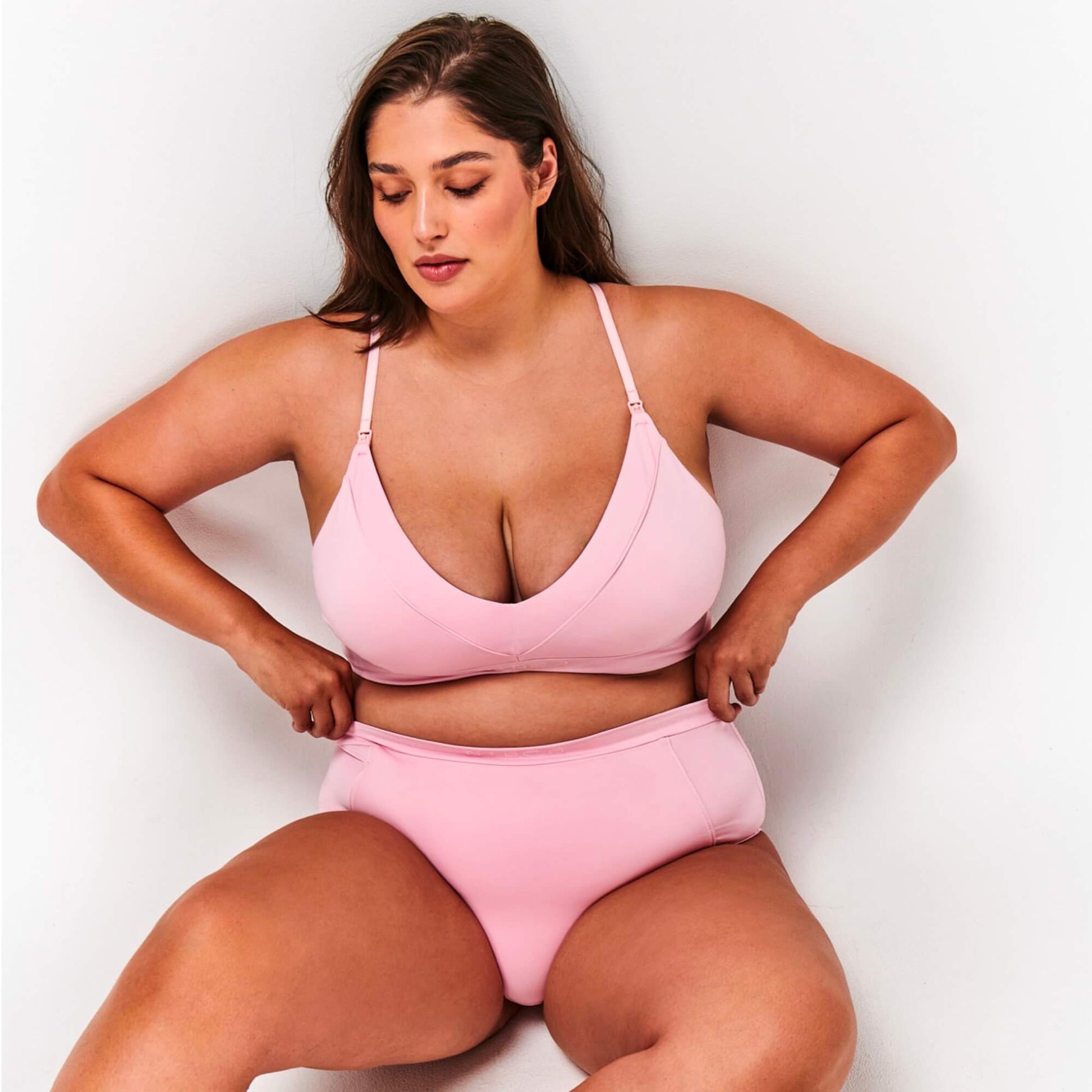 Model sits and wears NipCo Soft Pink Maternity Bra and High Waisted Briefs