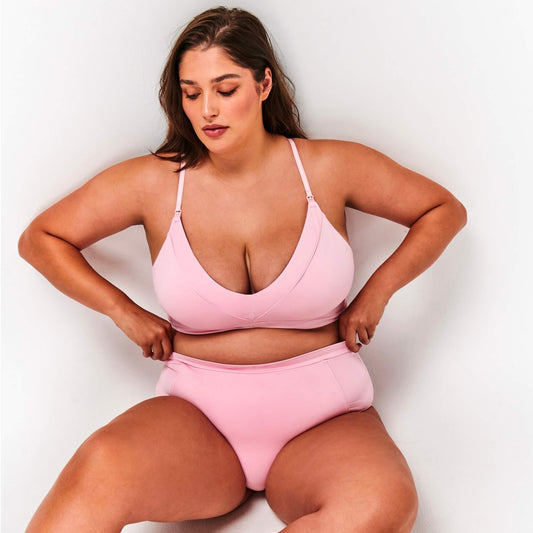 Model sits and wears NipCo Soft Pink Maternity Bra and High Waisted Briefs