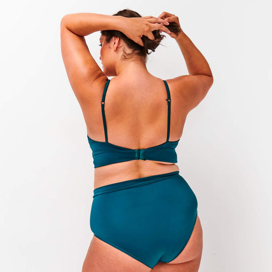 Model turns away to show the back of the NipCo Maternity Bra and High Waisted Briefs in Teal
